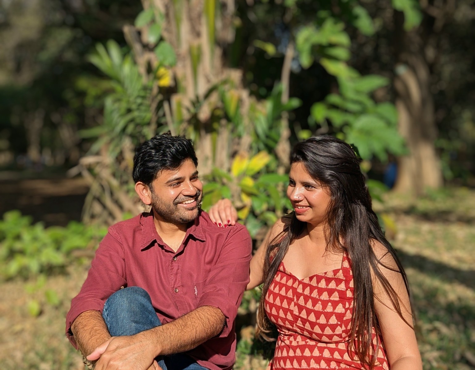 Snigdha and Somnath smiling at one another in a sunlit garden