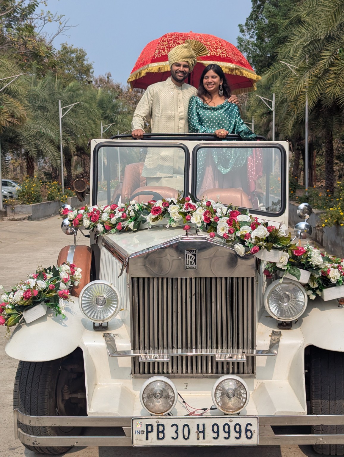 Snigdha and Somnath standing in a decorated vintage wedding car